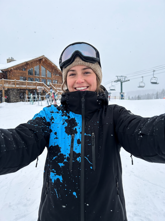 Selfie outside a mountain lodge wearing the StormShift jacket in Arctic Blue